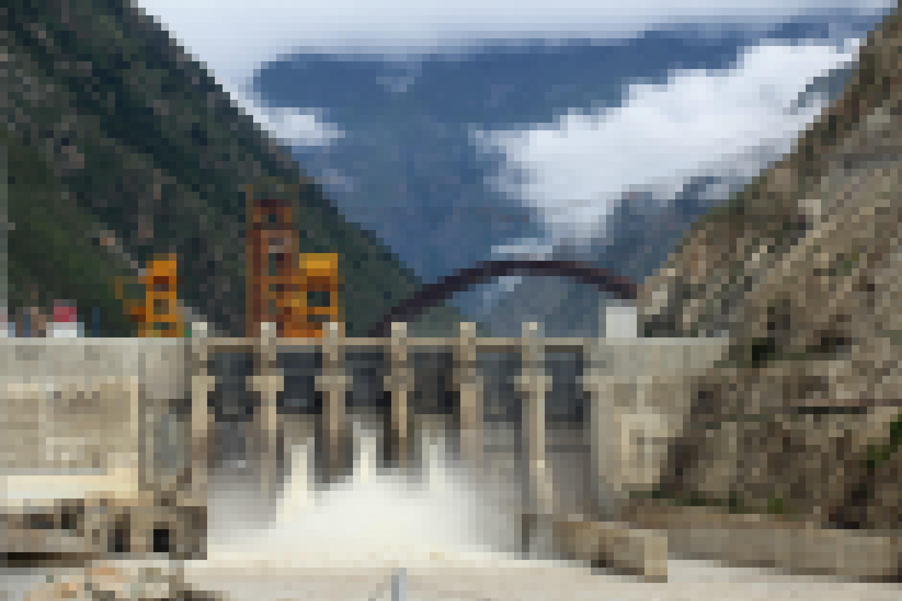 Großer Staudamm in einem engen Tal, Wasser schießt durch die Turbine