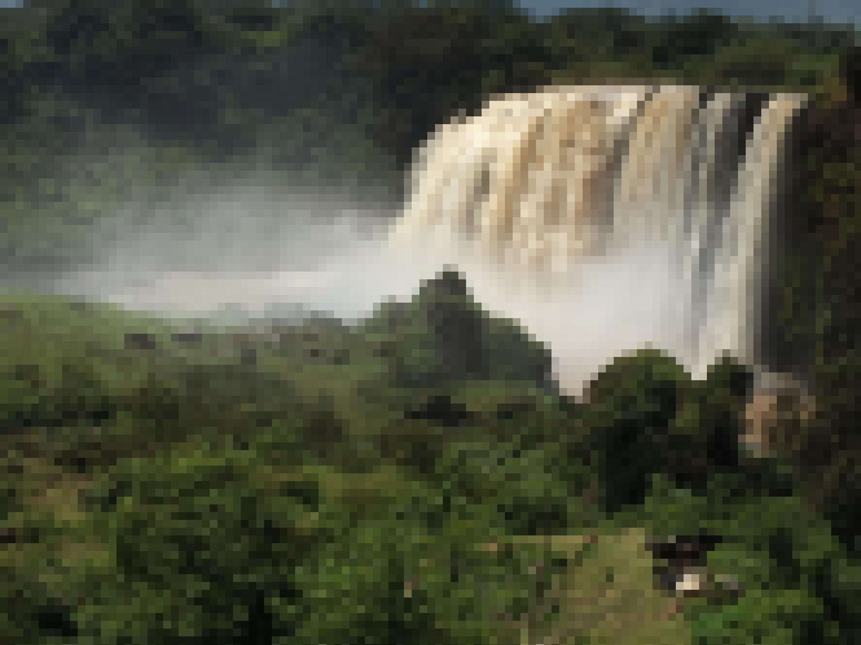 Ein großer Wasserfall am Blauen Nil inmitten von üppiger Vegetation, im Vordergrund grasende Kühe.