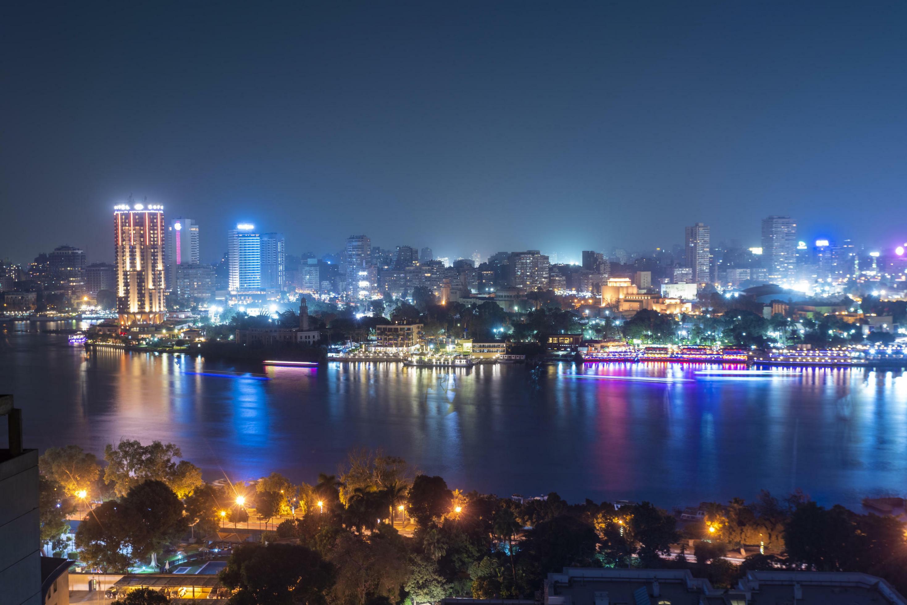 Die Skyline von Kairo bei Nacht mit dem Nil im Vordergrund.