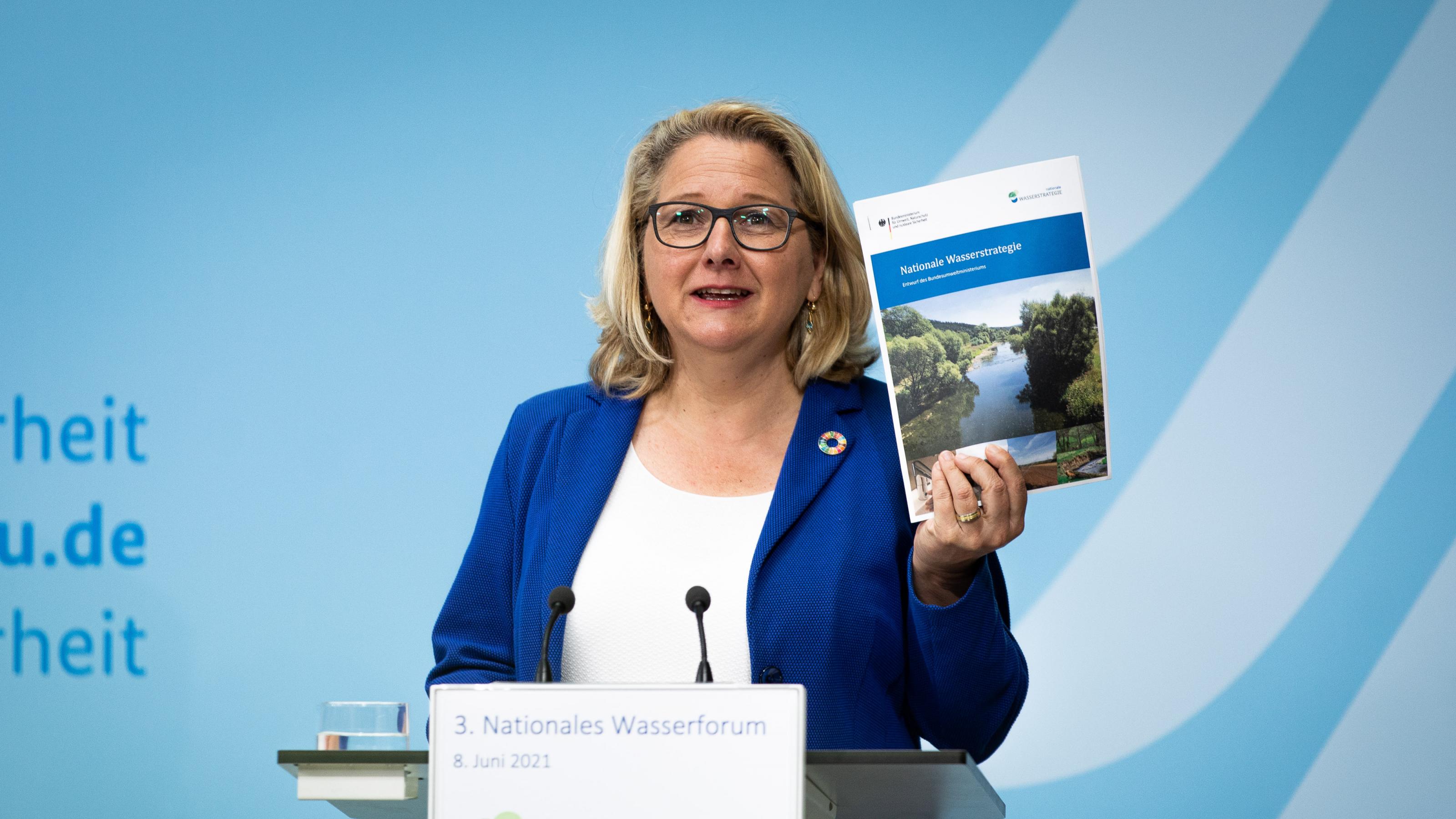 Bundesumweltministerin Svenja Schulze stellte eine erste „Nationale Wasserstrategie “am 8. Juni 2021 anlässlich der Eröffnung des 3. Nationale Wasserforums in Berlin vor. Das Bild zeigt die Ministerin am Rednerpult. Sie hält die Publikation mit dem Titel „Nationale Wasserstrategie“ hoch, so dass das Publikum sie gut sehen kann.