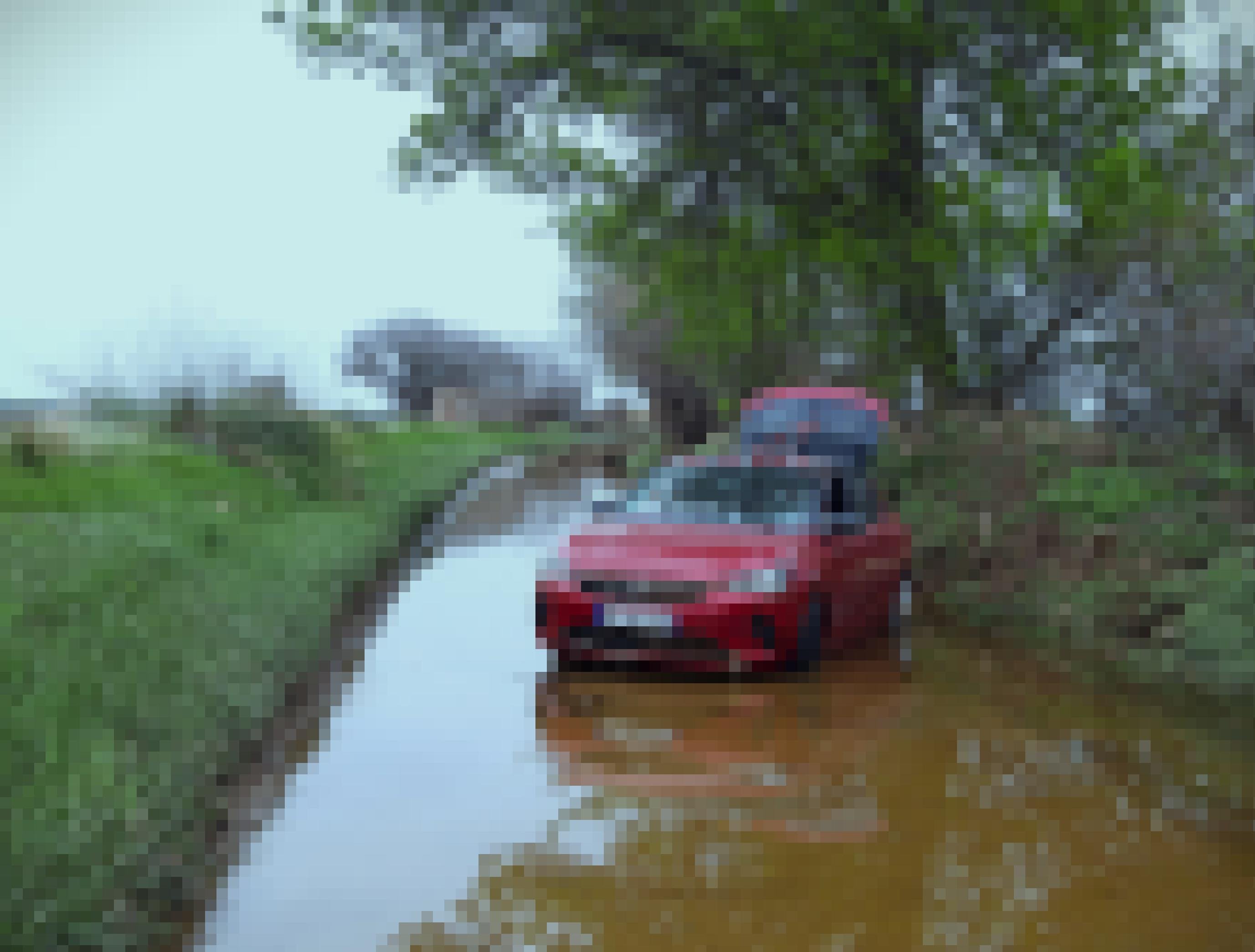 Eine Fahrstraße konvertierte zur Wasserstraße und mitten drinnen steht ein verlassener roter PKW, dem das Wasser bis über den Kühlerrost ging.