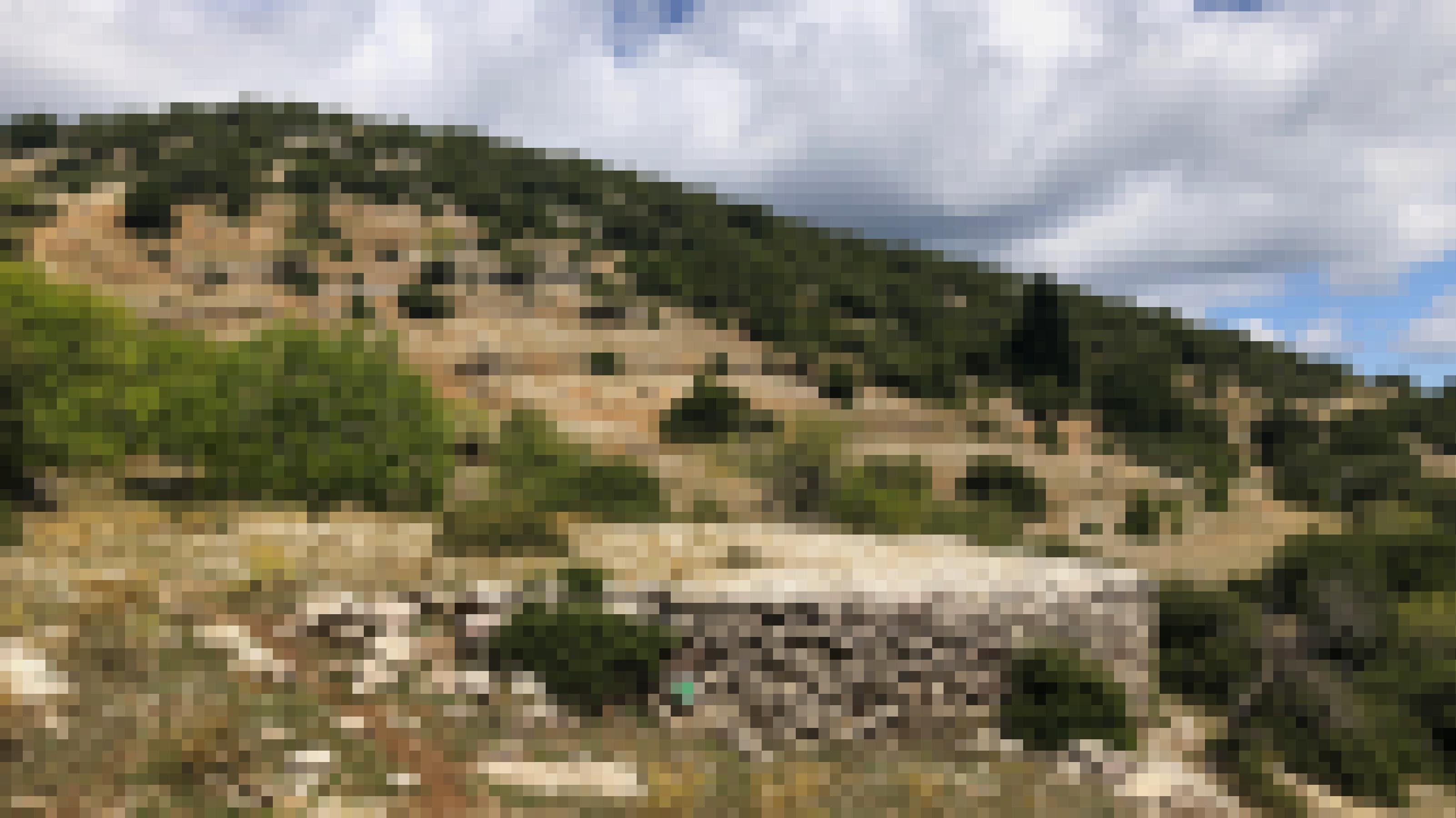 Eine Steinmauer im Vordergund, dahinter karge Wiesen und immer wieder Mauern.