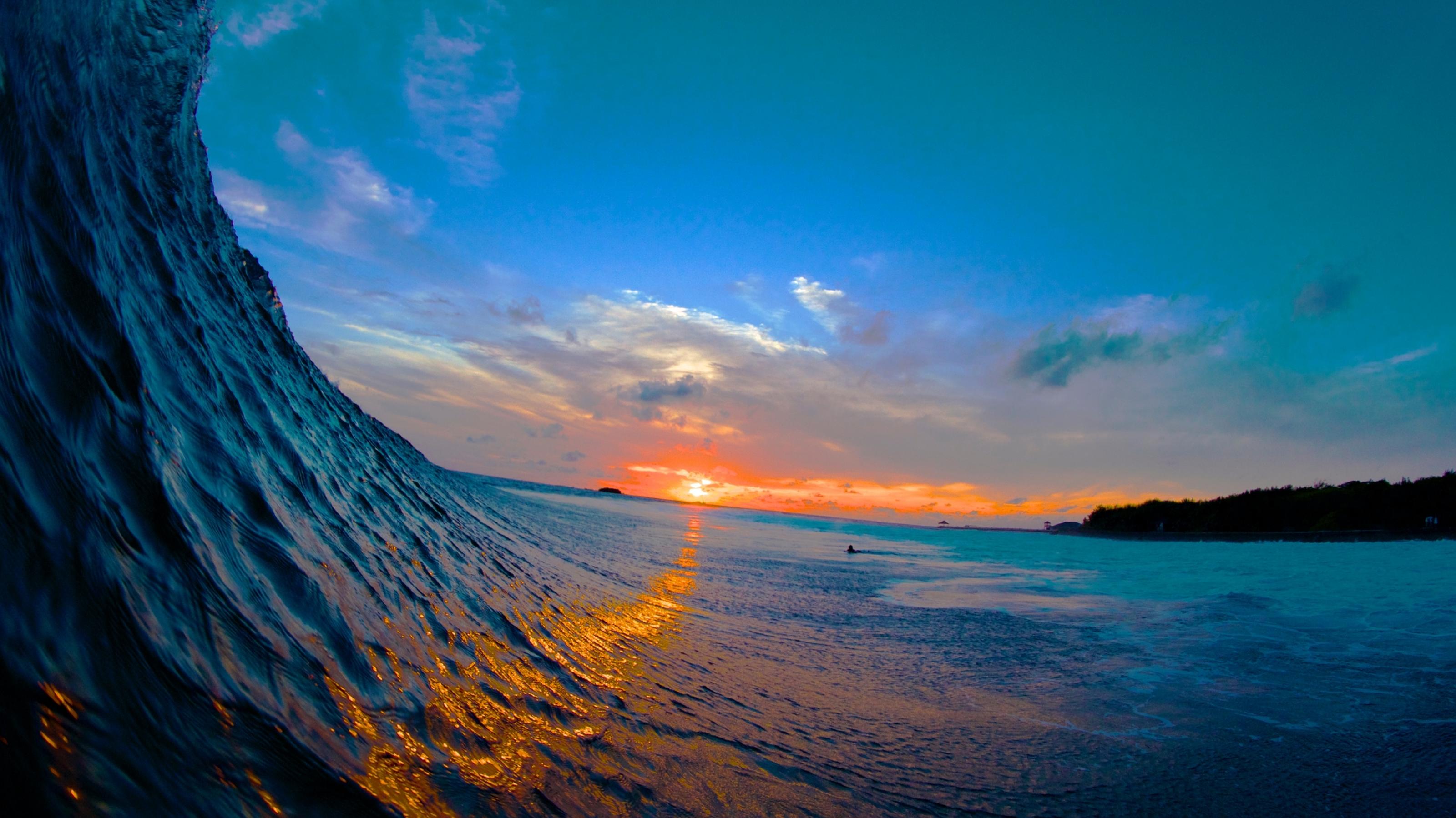 Vor dem Sonnenuntergang türmt sich eine große Welle auf.