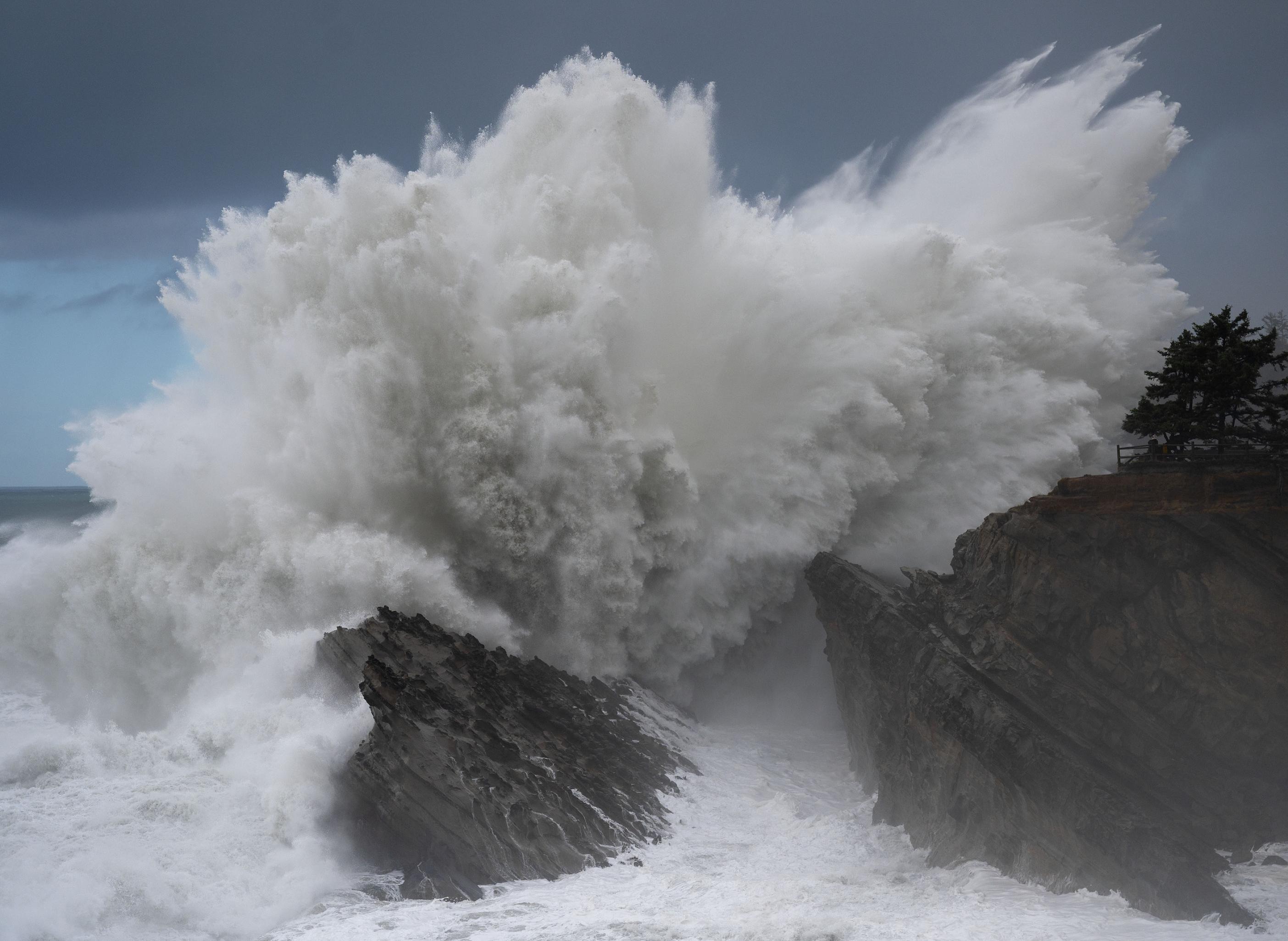 Das Bild zeigt, wie eine Welle voller Kraft gegen Felsen kracht.