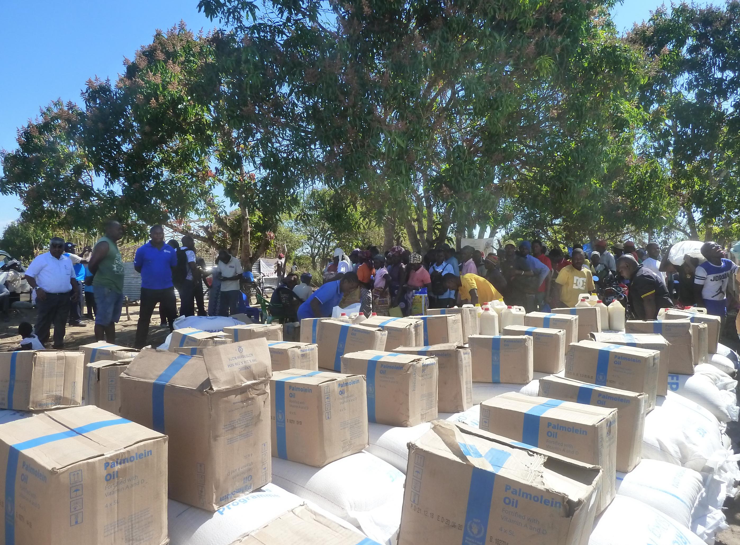 Das Bild zeigt Säcke und Kisten mit Lebensmitteln, die gerade von einem LKW des Welternährungsprogramms abgeladen wurden. Drumherum warten bereits die Hilfsbedürftigen. Mosambikanerinnen, die durch den Zyklon 2019 alles verloren haben.