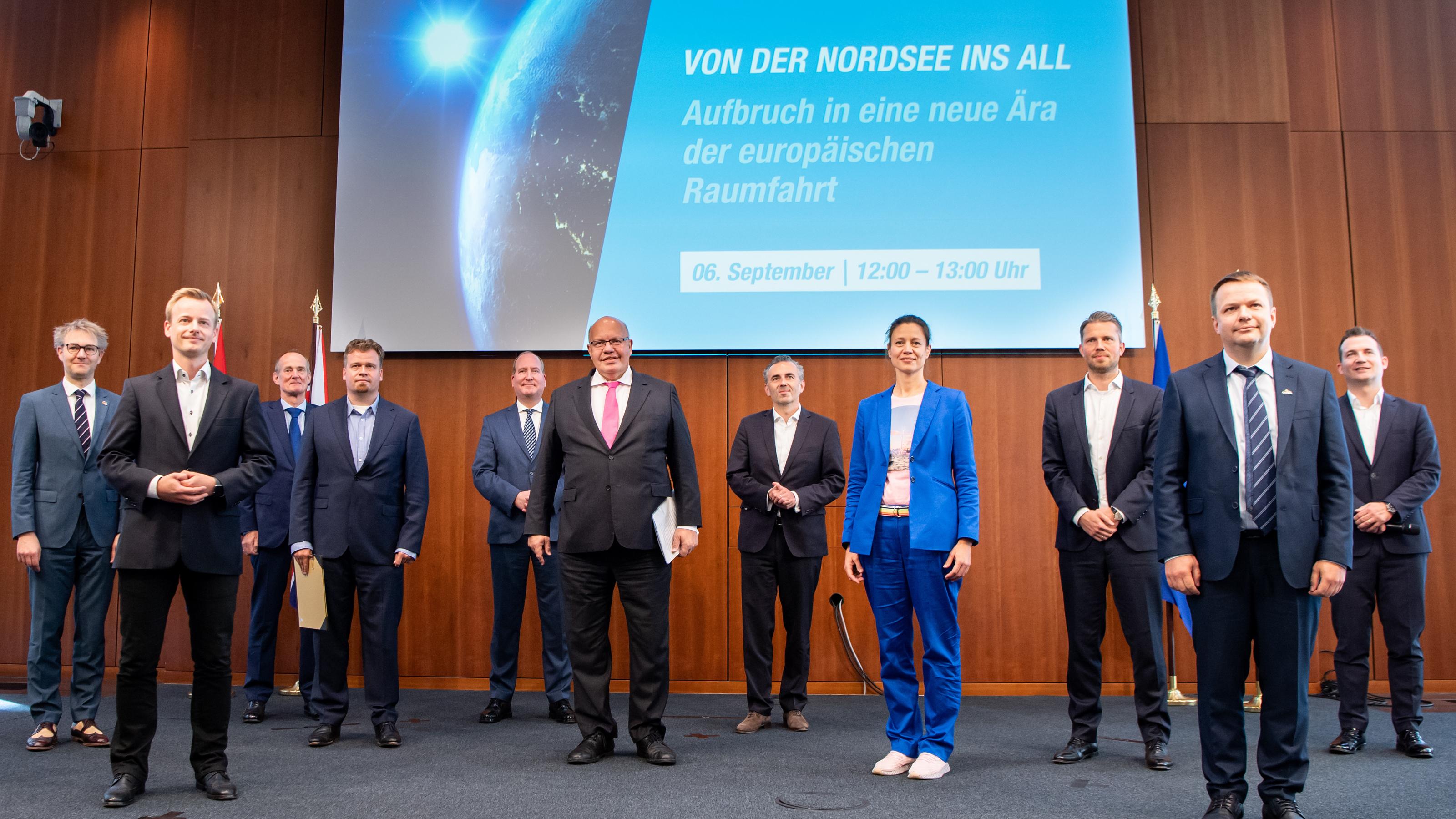 Auf einer Bühne stehen rund um Wirtschaftsminister Peter Altmaier diverse Vertreter von Raumfahrt-Start-ups. Auf einer Leinwand steht der Titel der Veranstaltung: "Von der Nordsee ins All".