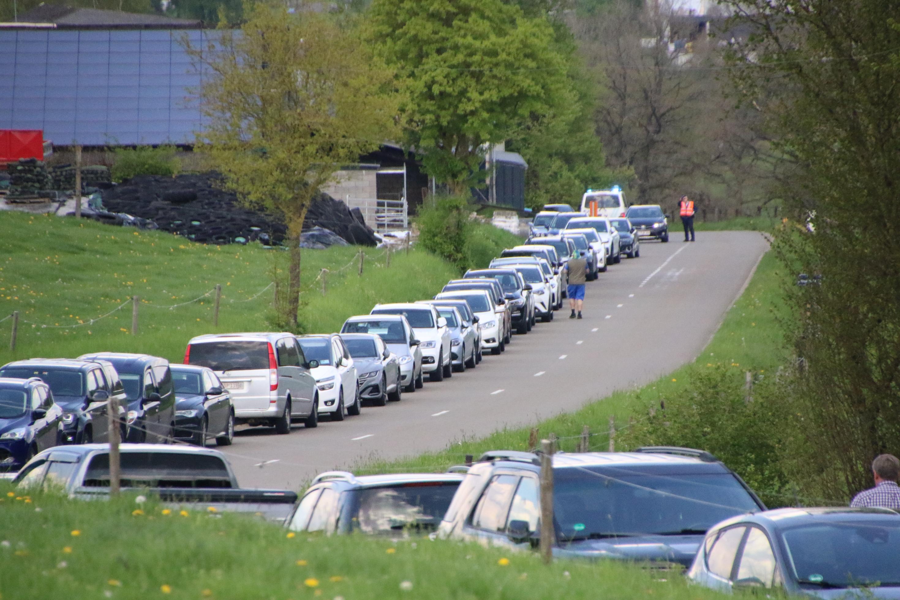 Unzählige Autos parken am Rand einer Landstraße.