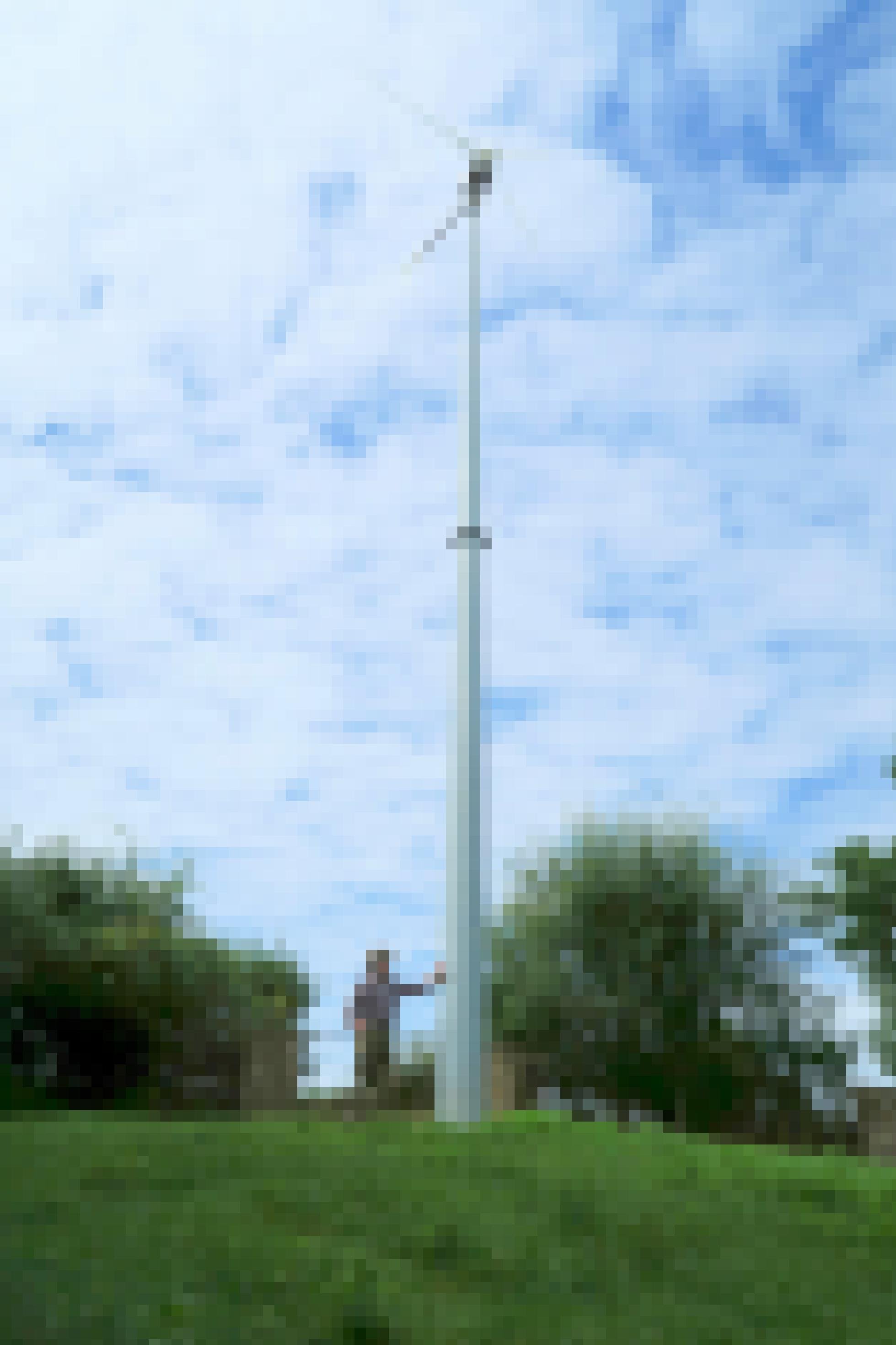Ein Mann lehnt an den Mast eines kleinen Windrades