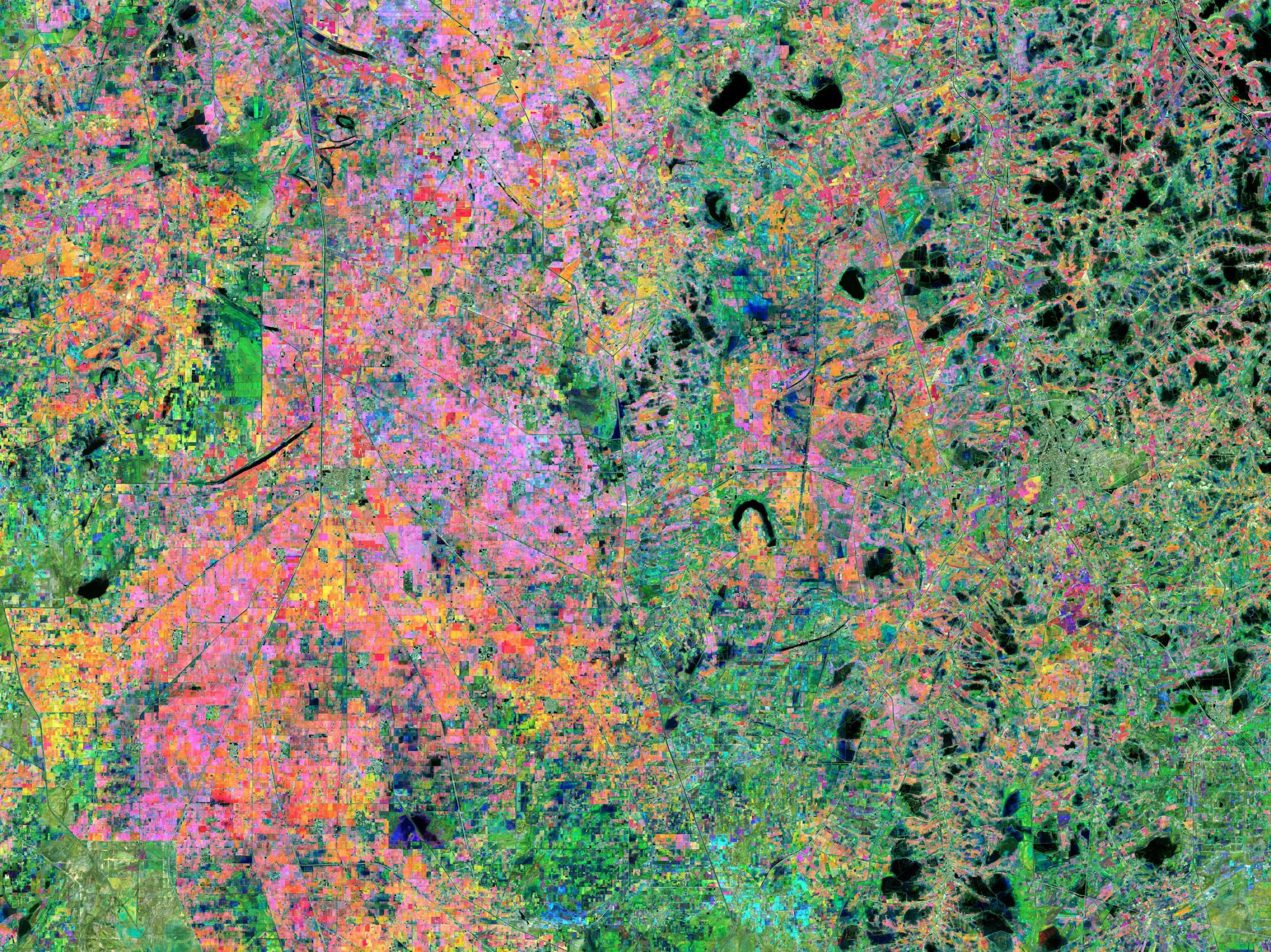 Satellitenbild in Fremdfarben, die aus der Landschaft ein Mosaik aus Rosa, Grün, Blau und Rot machen.