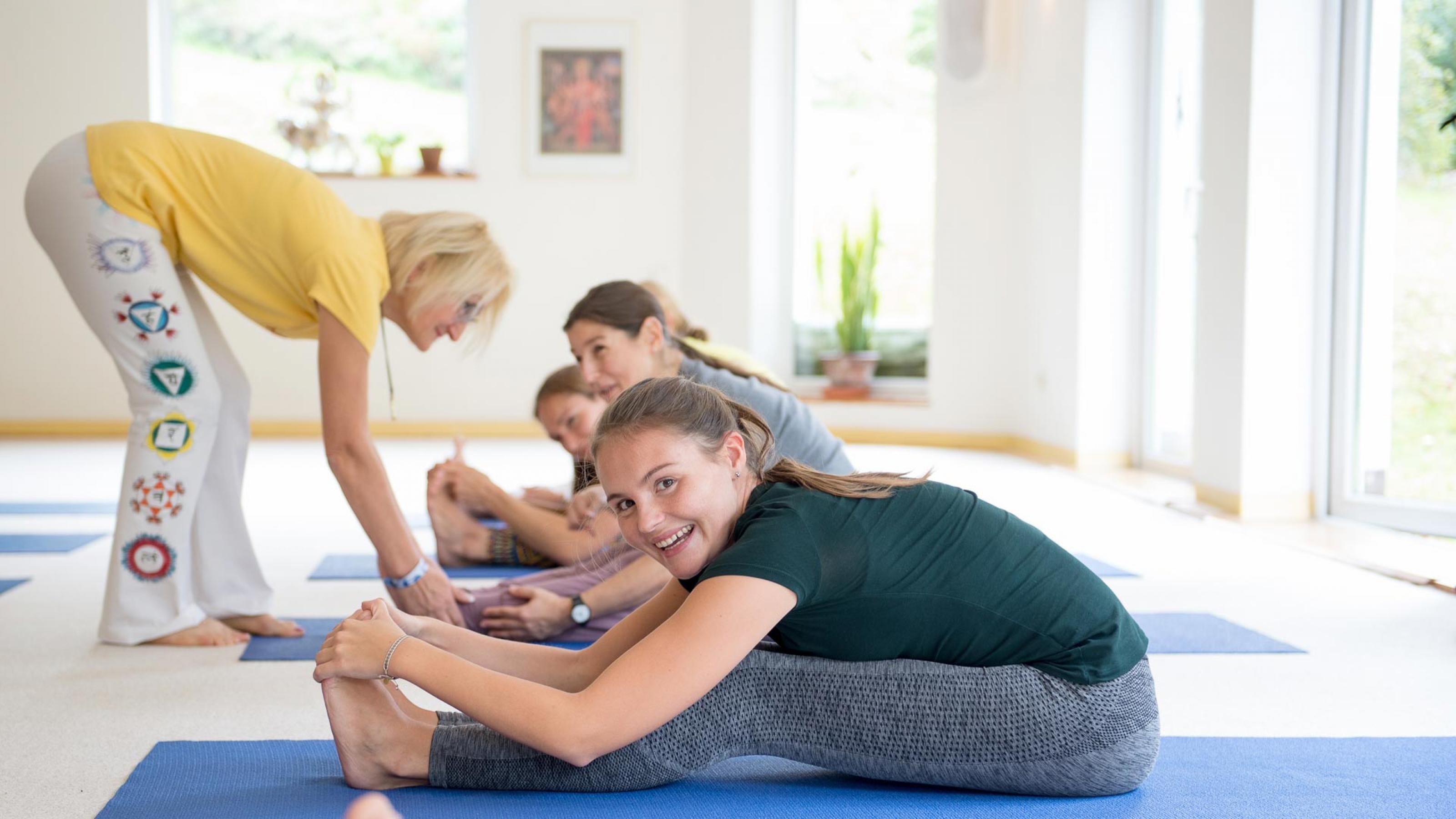 Mehere Frauen werden von einer Ygoa-Lehrerin beim Yoga angeleitet.