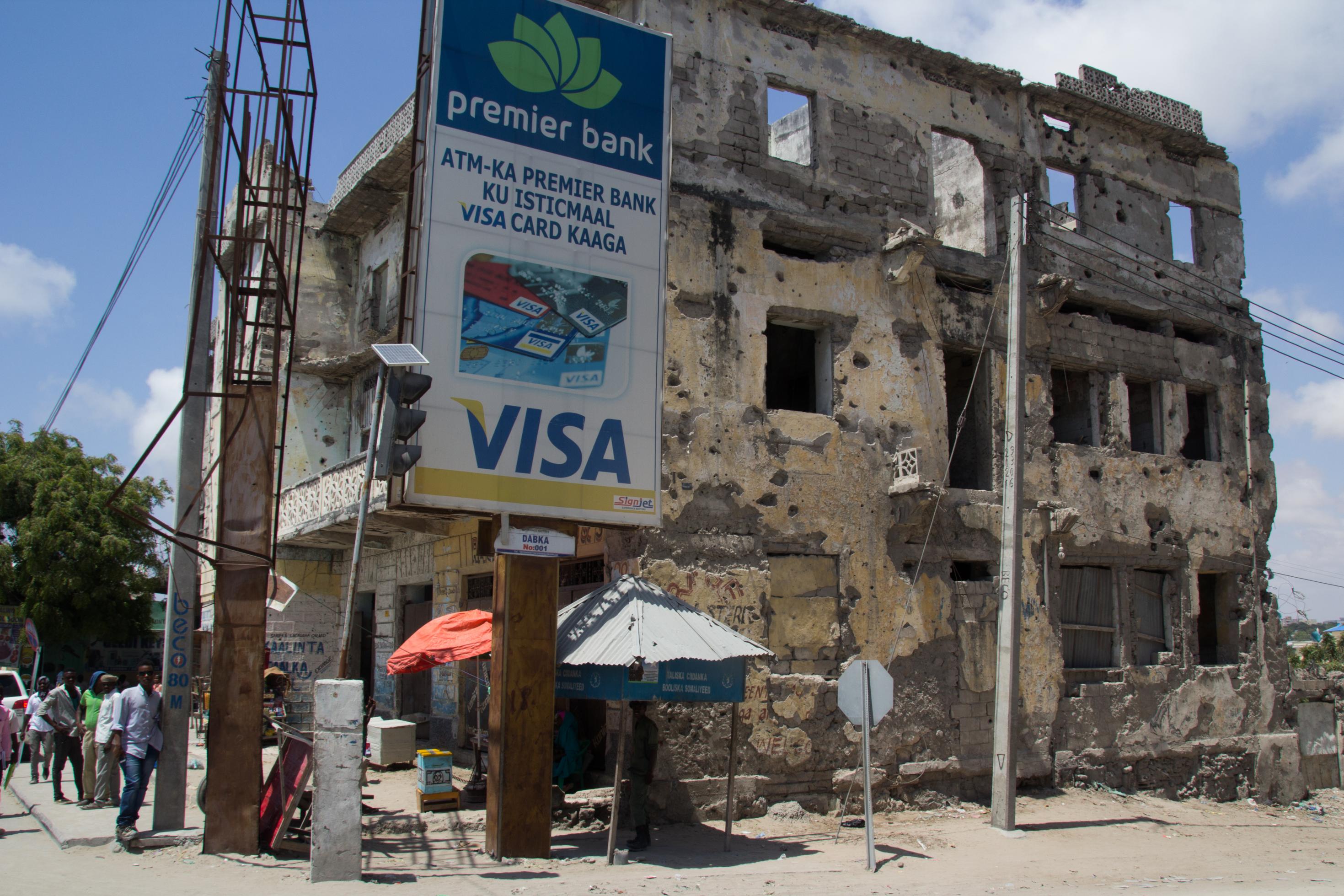 Vor einer Kriegsruine im Zentrum der somalischen Hauptstadt Mogadischu steht eine große Werbetafel für Visa-Kreditkarten. In der Nachkriegszeit boomen Geschäfte aller Art.