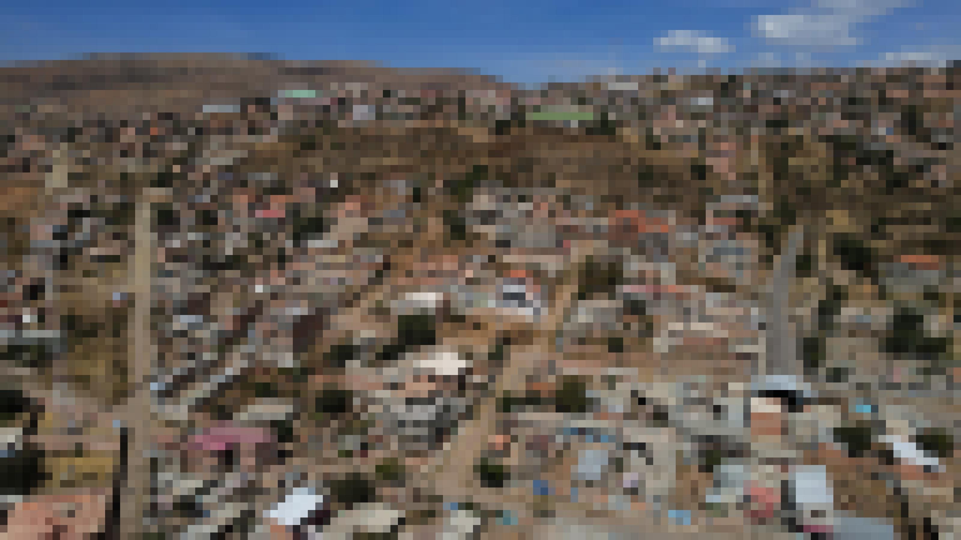 Panorama-Foto aus Luft von einem staubigen Hang mit großteils unverputzten Häusern und unasphaltierten Straßen. Die wenige Vegetation ist braun statt grün.