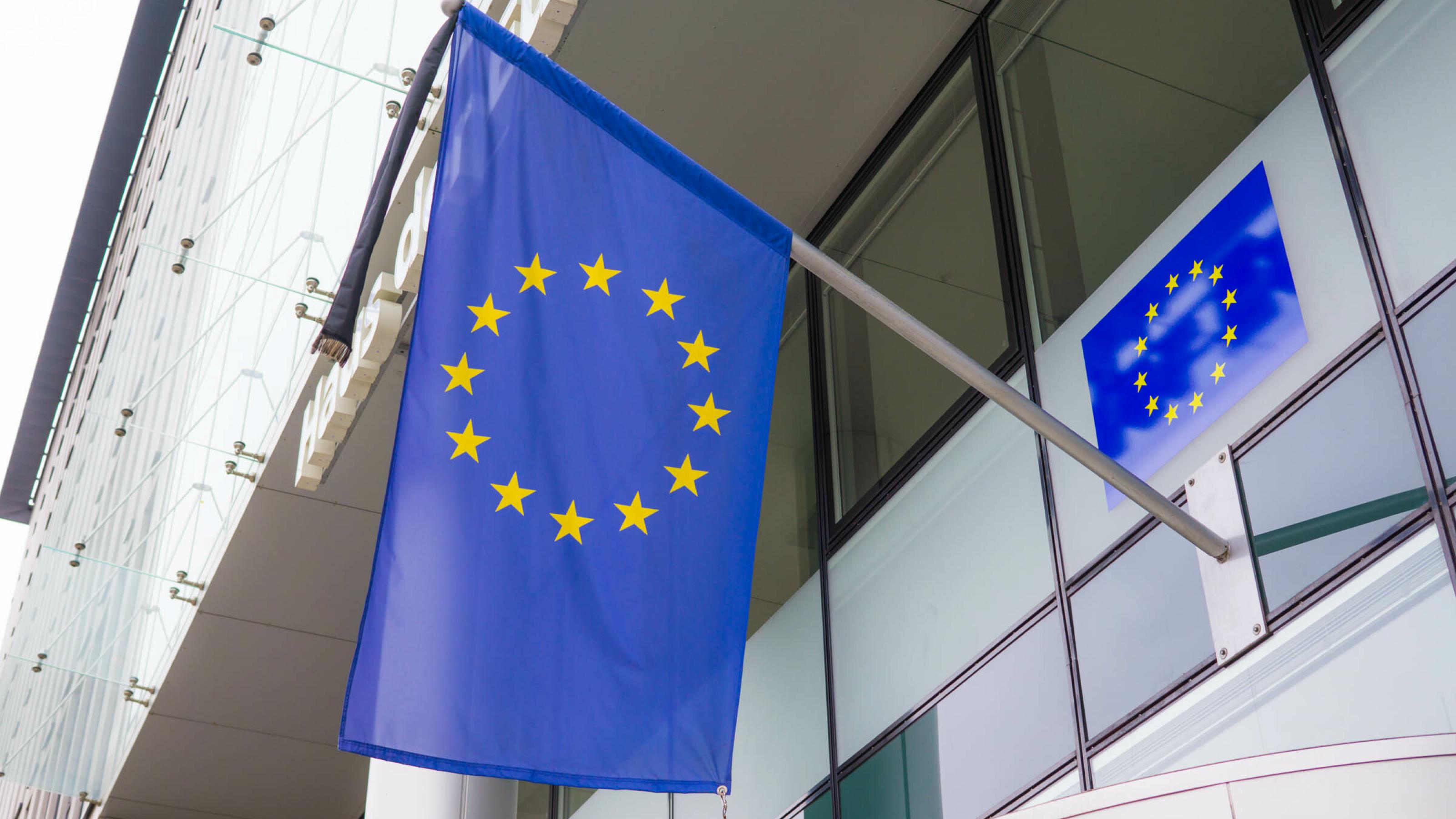 Ausschnitt der Fassade eines modernen Bürogebäudes mit EU-Fahne.